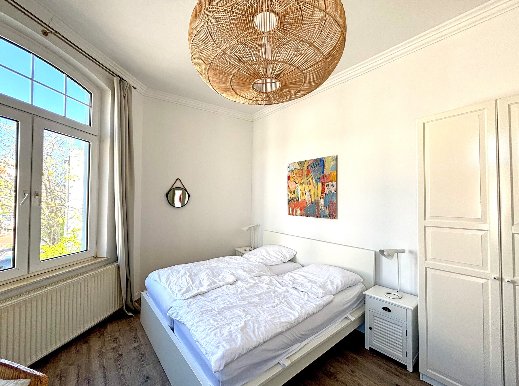 Schlafzimmer mit Holzbett und buntem Wandbild
