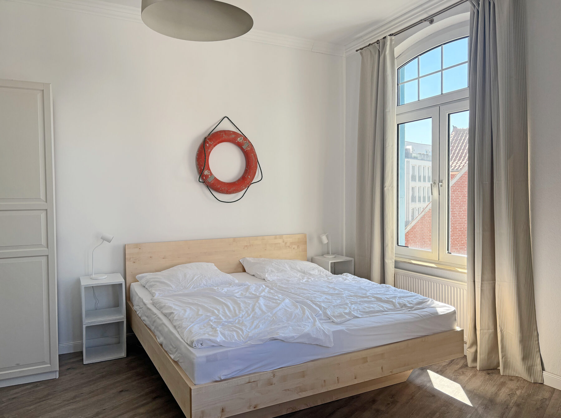 Schlafzimmer mit Doppelbett und maritimem Deko-Rettungsring